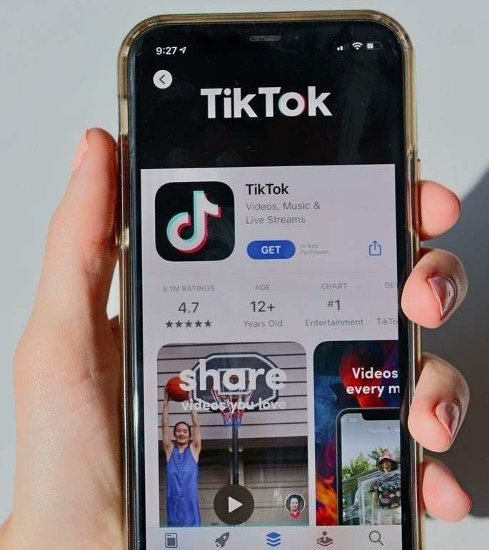 một người đang cầm điện thoại trên cửa hàng ứng dụng tải xuống TikTok