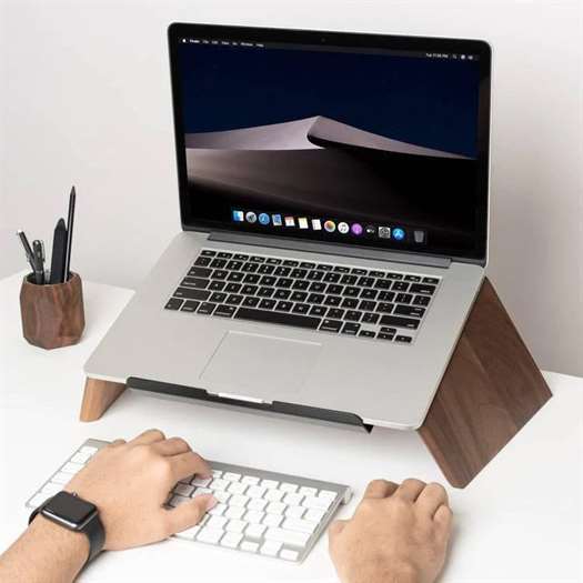 Cận cảnh văn phòng tại nhà được thiết lập nơi bàn tay gõ bàn phím và máy tính xách tay được đặt trên giá gỗ