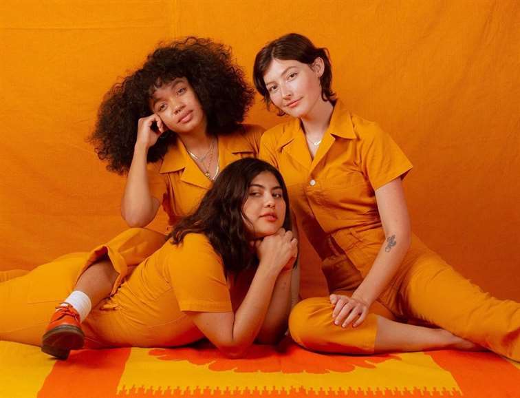Ba người mẫu mặc áo liền quần màu cam của Big Bud Press trên nền màu cam
