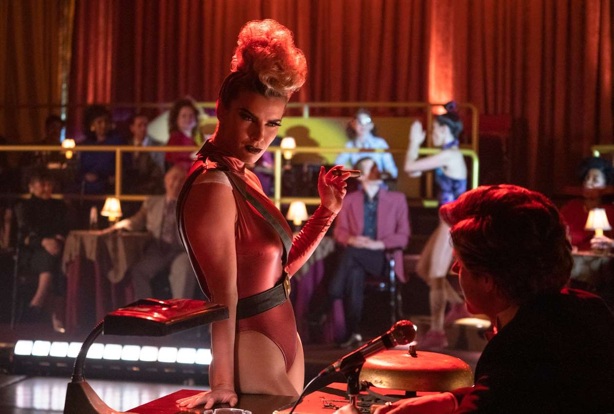 Debbie - người thường đóng vai Liberty Belle, hóa trang thành Zoya the Destroya trong buổi biểu diễn GLOW - nói chuyện với Bash (phát thanh viên) với điếu xì gà trên tay. 