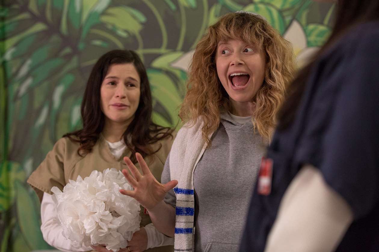 Nicky Nicholson cổ vũ trong khi Lorna Morello cầm hoa và khóc trên nền trong một tập của Orange Is the New Black.