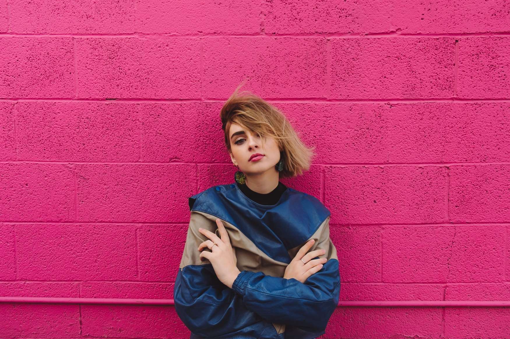 Người mẫu áo len colorblock trên bức tường màu hồng